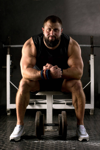 Powerlifter with strong arms is preparing a weightlifting. Muscular man training in the gym. Healthy lifestyle concept. - Photo, image