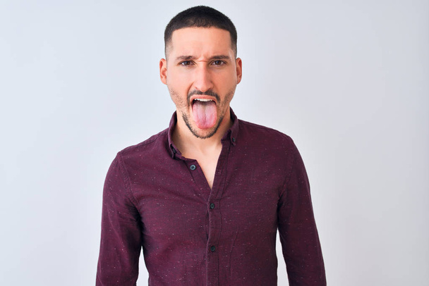 Young handsome business man standing over isolated background sticking tongue out happy with funny expression. Emotion concept. - Фото, зображення