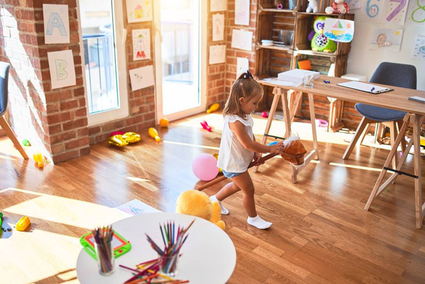 Jovem menina loira bonita garoto desfrutando jogar escola com brinquedos no jardim de infância, sorrindo feliz jogando em casa
 - Foto, Imagem