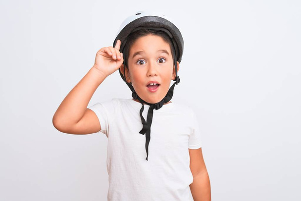 Piękny chłopiec noszący kask bezpieczeństwa roweru stojący nad odizolowanym białym tłem wskazującym palcem na udany pomysł. Wyjechany i szczęśliwy. Numer jeden.. - Zdjęcie, obraz