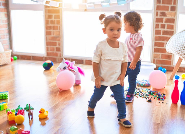 Adoráveis crianças de pé em torno de lotes de brinquedos no jardim de infância
 - Foto, Imagem