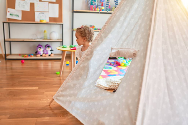 Beautiful caucasian infant playing with toys at colorful playroom. Happy and playful with indian tent at kindergarten. - Valokuva, kuva