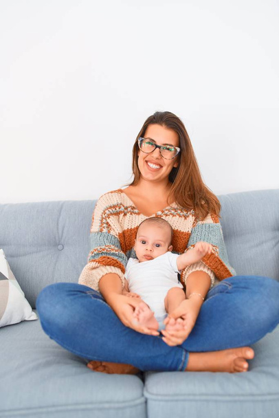 Young beautiful woman and her baby on the sofa at home. Newborn and mother relaxing and resting comfortable - Photo, Image
