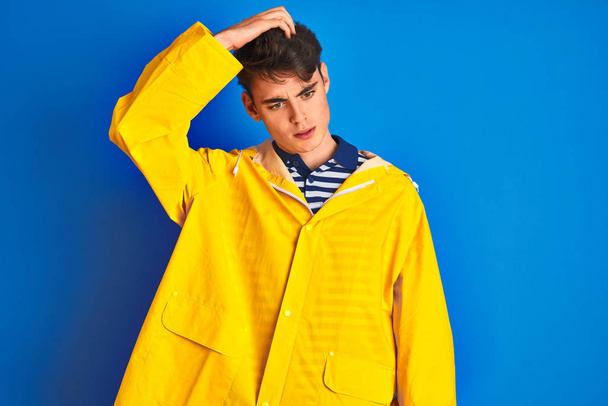 Adolescente pescatore ragazzo indossa impermeabile giallo su sfondo isolato confondere e chiedersi circa domanda. Incerto con il dubbio, pensando con mano sulla testa. Concetto pensieroso
. - Foto, immagini