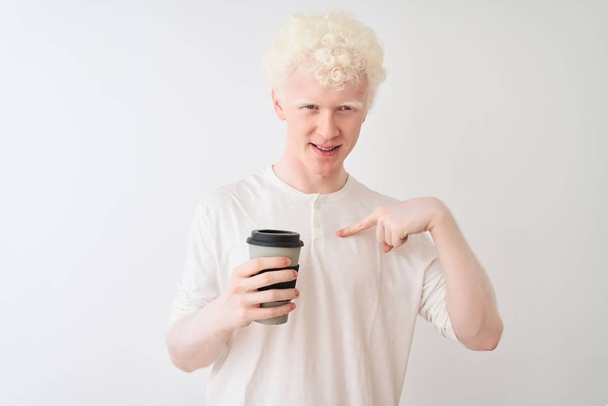 Молодий альбіно блондинка п'є каву, що стоїть над ізольованим білим тлом з несподіваним обличчям, спрямованим пальцем до себе
 - Фото, зображення