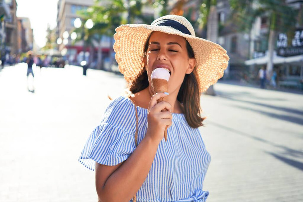 Young beautiful woman eating ice cream cone walking down the street of Tenerife on a sunny day of summer on holidays - Photo, Image
