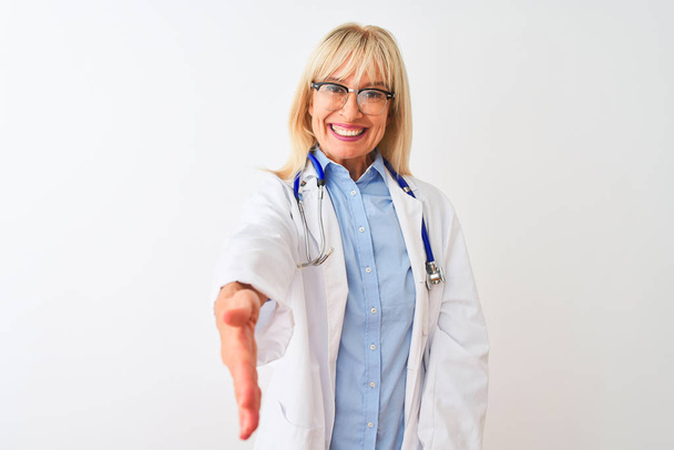 Keski-ikäinen lääkäri nainen yllään lasit ja stetoskooppi yli eristetty valkoinen tausta hymyilevä ystävällinen tarjoaa kädenpuristus kuin tervehdys ja kutsuva. Menestyksekäs yritys
. - Valokuva, kuva