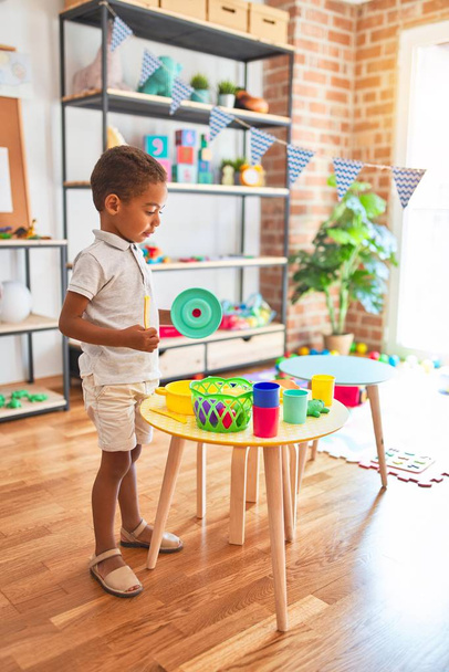 Beau bambin afro-américain jouant avec de la nourriture en plastique et des couverts jouet à la maternelle
 - Photo, image