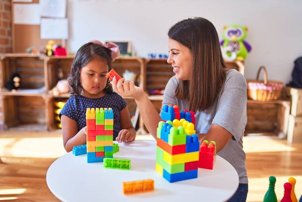 Güzel öğretmen ve küçük kız anaokulunda inşaat bloklarıyla oynuyorlar. - Fotoğraf, Görsel