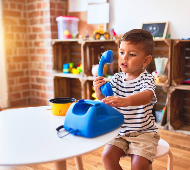 Beautiful toddler boy playing with vintage blue phone at kindergarten - 写真・画像