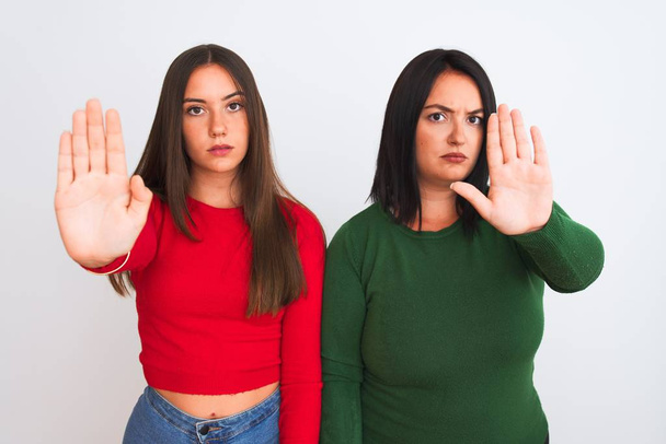 Young beautiful women wearing casual clothes standing over isolated white background doing stop sing with palm of the hand. Warning expression with negative and serious gesture on the face. - Photo, Image