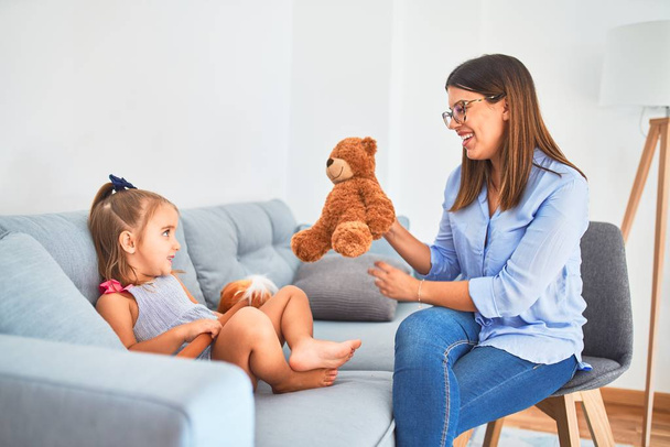 Young therapist woman speaking and treating child, counselor and behaviour correction at pedagogue payroom playing with stuffed animal - Foto, Imagem