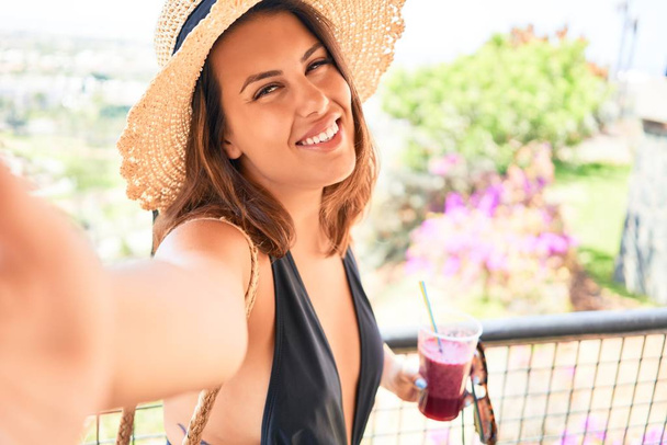 Mooie vrouw op badpak neemt een selfie met smartphone in hotel resort op zomervakantie - Foto, afbeelding