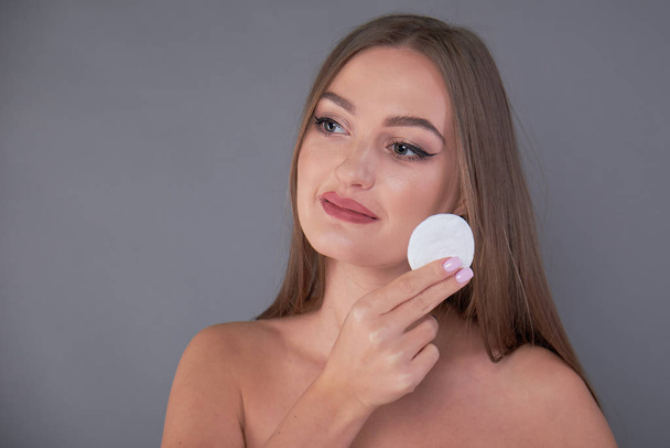 Healthy fresh girl removing makeup from her face with cotton pad. woman with a sponge wihte background cotton pad problem skin - Foto, immagini