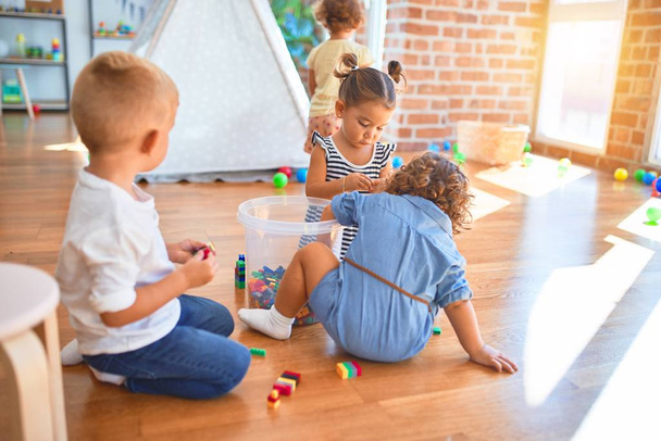 Adorable group of toddlers playing around lots of toys at kindergarten - Photo, image