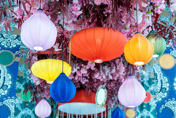 Lanternas chinesas multicoloridas com flores durante o dia
 - Foto, Imagem