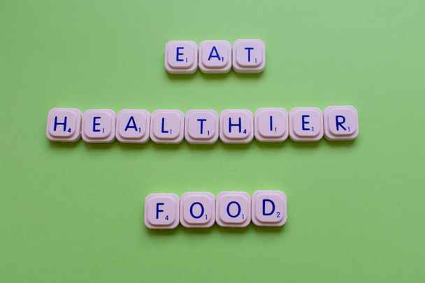 slogan motivazionale: Mangiare cibo più sano, su uno sfondo verde fatto con le lettere di gioco
 - Foto, immagini