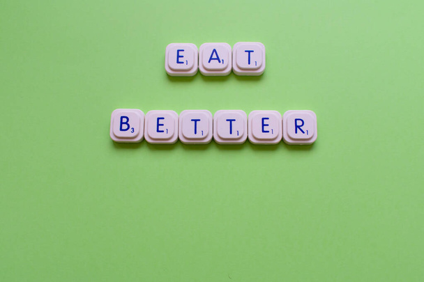 Motivációs szlogen: Egyél jobban, zöld háttérrel készült játékbetűkkel - Fotó, kép