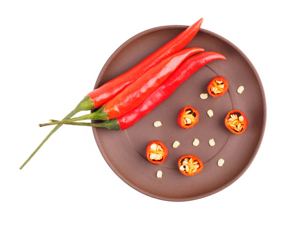 Red chili on brown clay plate isolated on white. Indian cuisine, - Photo, Image