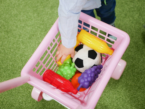 Baby and shopping concept. Un niño compra juguetes para sí mismo. Niño y carro. - Foto, Imagen