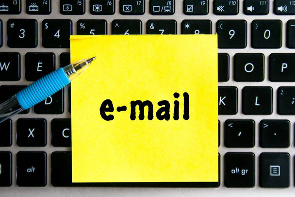 Napis "email" na żółtej kartce papieru naklejkowego na tle klawiatury komputera. - Zdjęcie, obraz