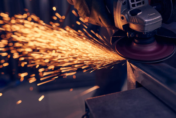 Worker cutting metal with grinder. Sparks while grinding iron - Foto, afbeelding
