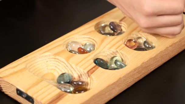 juego de mangala de madera, tablero de juego de mangala y canicas de vidrio, sobre fondo negro
 - Metraje, vídeo