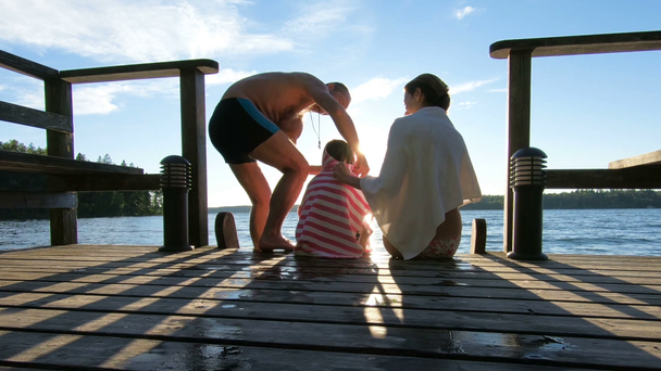 A man wraps a towel around his wife and daughter after swimming in the lak - Footage, Video