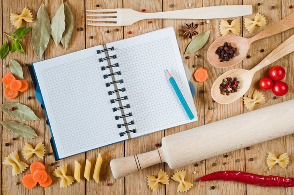 Notebook aberto para receitas, legumes e especiarias em um t de madeira
 - Foto, Imagem