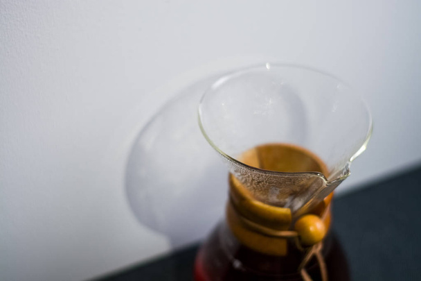 Bir tonluk beyaz zemin üzerinde koyu kahve dolu cam kap büyük ve alışılmadık gölgelerin yansıması.. - Fotoğraf, Görsel