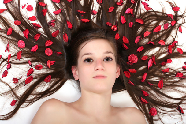 Красива жінка лежить на білому фоні студії з квітами у волоссі
. - Фото, зображення
