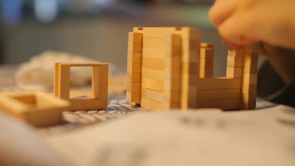 Close-up child builds a small house from a wooden constructor. - Πλάνα, βίντεο
