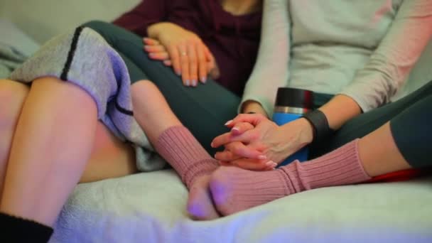 Close-up of the hands of two girls sitting and talking on the couch. - Felvétel, videó
