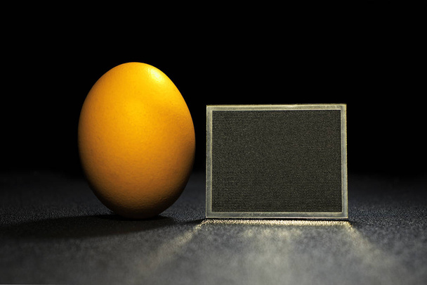 Yellow egg with place for text. Yellow egg on black background. opy space. Food photo - Photo, Image