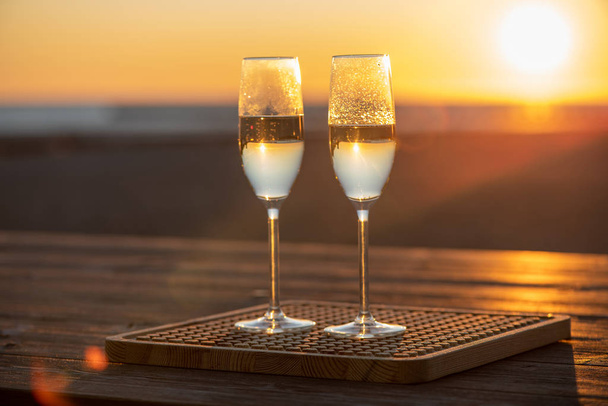 dwa kieliszki szampana na stole o zachodzie słońca - Zdjęcie, obraz