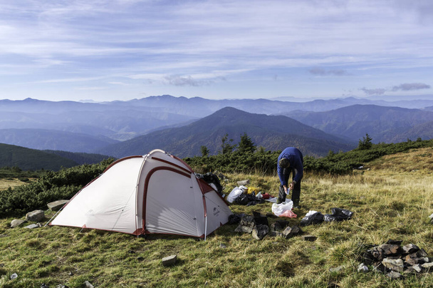 Base camp in the mountains. A tourist collects things for a hike. - Photo, Image