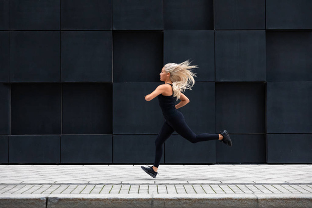 fitte junge Frau läuft in minimalistischer urbaner Umgebung - Foto, Bild