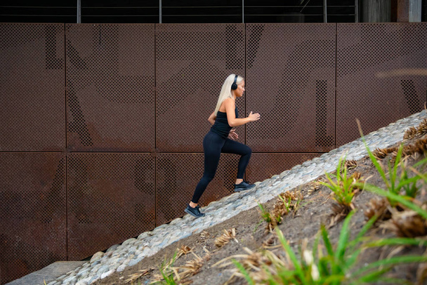 Přizpůsobit atraktivní sportovní ženy běží rychle po schodech proti kovové zdi ve městě - Fotografie, Obrázek