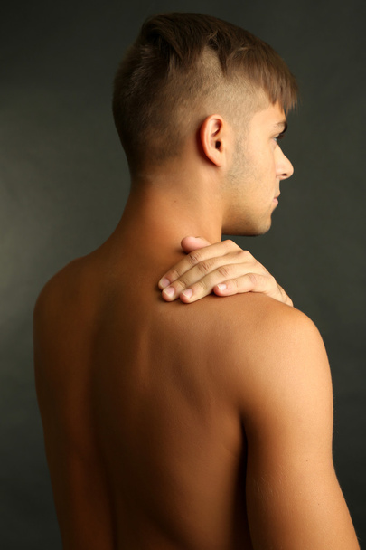 Young man with neck pain on grey background - Фото, изображение