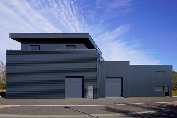 gray large industrial building exterior warehouse grey hangar exterior with rolling gates in blue sky - Photo, Image