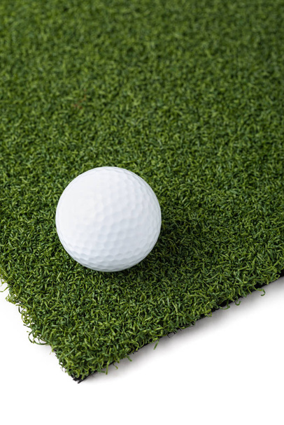 Bola de golfe descansando na seção de grama relva artificial em fundo branco
 - Foto, Imagem