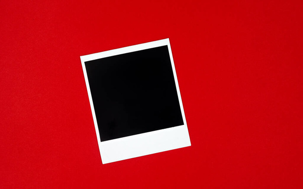 Оригінальна порожня біло-чорна поляроїдна рамка, що лежить на червоному тлі. Фоторамка
. - Фото, зображення