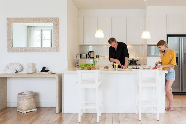 Paar kocht zu Hause einen Salat auf einer weißen Inselküche - Foto, Bild