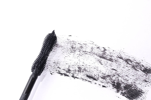 Applicator and black mascara smear for eyelashes on white background. Top view. - Valokuva, kuva