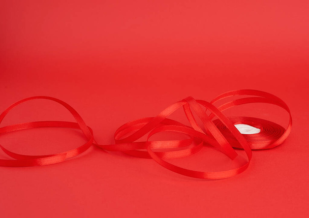 kroucené červené hedvábí lesklá stuha na červeném pozadí - Fotografie, Obrázek