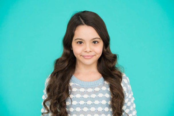 She is really cute. Happy girl child blue background. Small child wear long wavy hair. Little child with cute smile. Beauty salon. Fashion and style. Child care and childhood - Foto, afbeelding