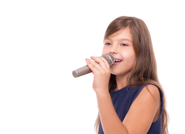 Pieni tyttö poseeraa mikrofonin kanssa laulamaan valkoisella taustalla
. - Valokuva, kuva