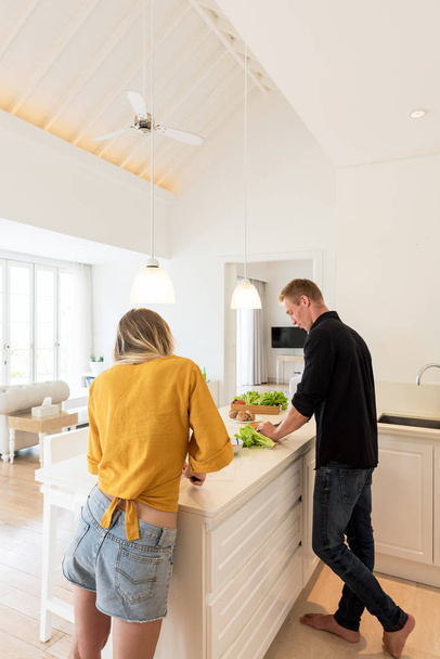 Couple faisant le déjeuner sur une cuisine îlot blanc à la maison
 - Photo, image