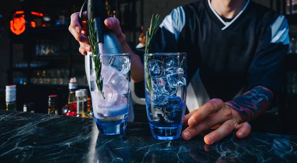 Baarimikko tekee alkoholia cocktaileja jäällä ja rosmariinilla baarissa
 - Valokuva, kuva