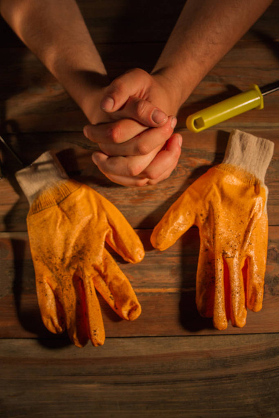Грязные рабочие перчатки и скрещенные руки
. - Фото, изображение